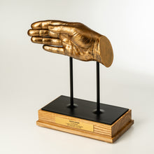 Load image into Gallery viewer, Gold hand sculpture on a black base with wooden stand against a white background