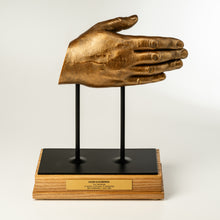 Load image into Gallery viewer, Bronze hand sculpture on a stand with a wooden base on a white background