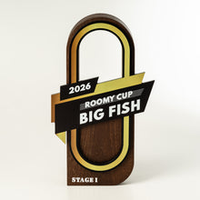 Load image into Gallery viewer, A wooden trophy plaque shaped like a large padlock, with black and gold ribbon graphics across the center reading '2026 ROOMY-CUP BIG FISH' and 'STAGE I' at the bottom, photographed on a clean white background.