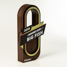 Load image into Gallery viewer, A wooden trophy plaque shaped like a large fish hook, with dark brown wood grain, a black and gold banner reading '2026 ROOMY CUP BIG FISH', and 'STAGE I' at the bottom, photographed on a clean white background.